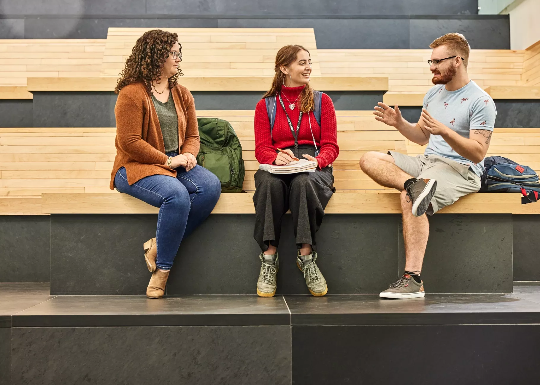 Alison Williams sitting on the wooden benches within the entrance of the Belknap Academic Building