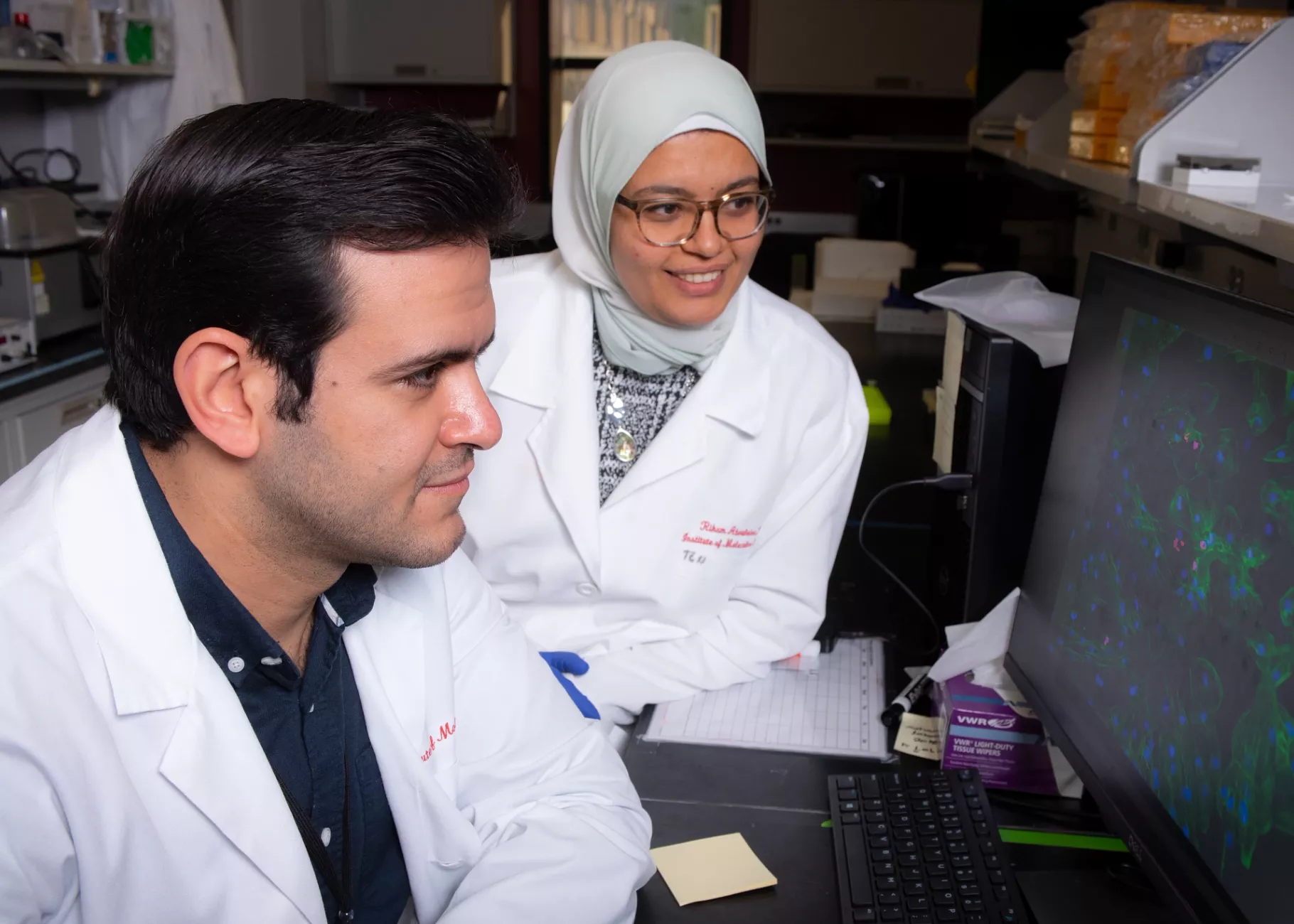 Two researchers look at a computer monitor