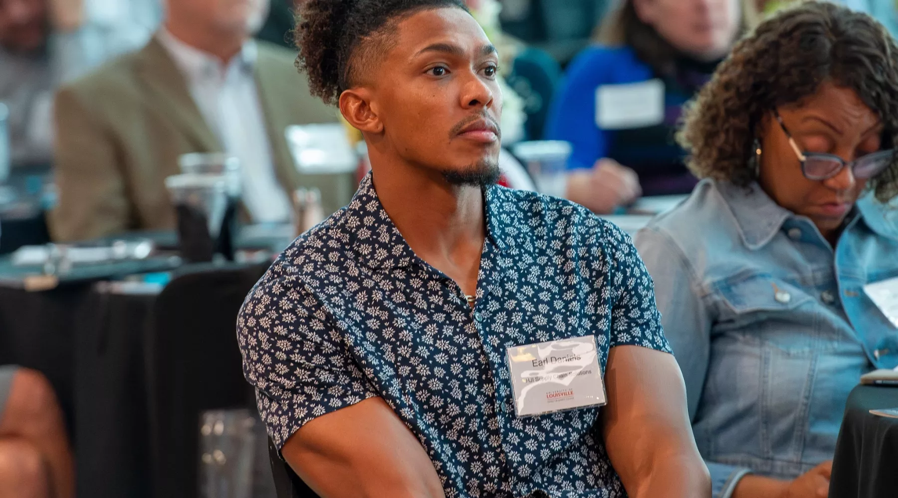 Audience members observe the presentation from the crowd