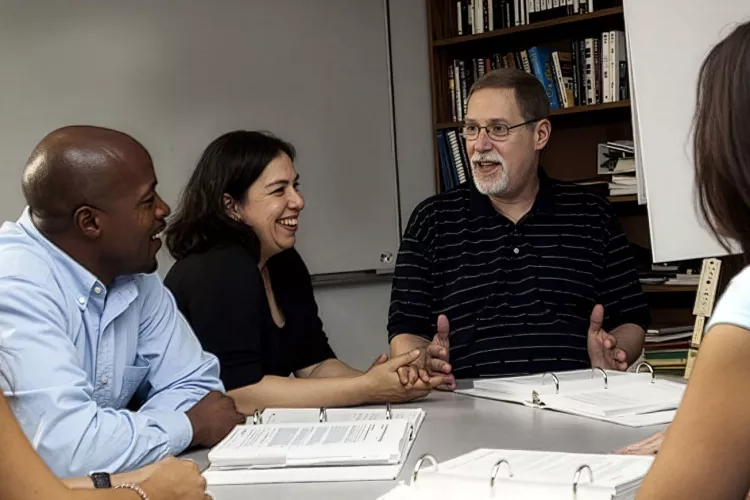 A group of scholars around a table discussing the engaged scholarship report
