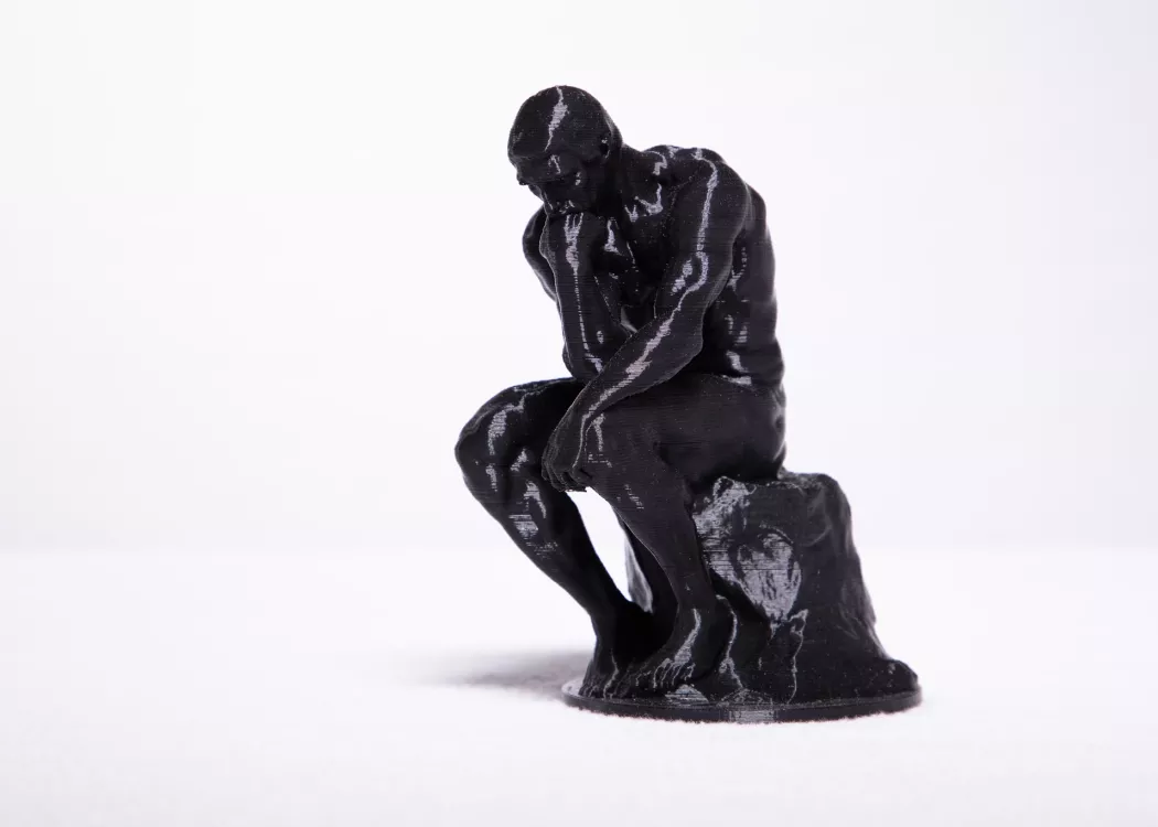 Small 3D printed version of "The Thinker" statue.
