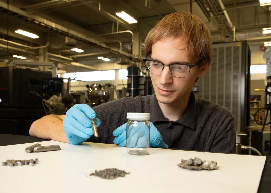 Mechanical engineering PhD student Brendon Dodge observing several materials involved in additive manufacturing research.