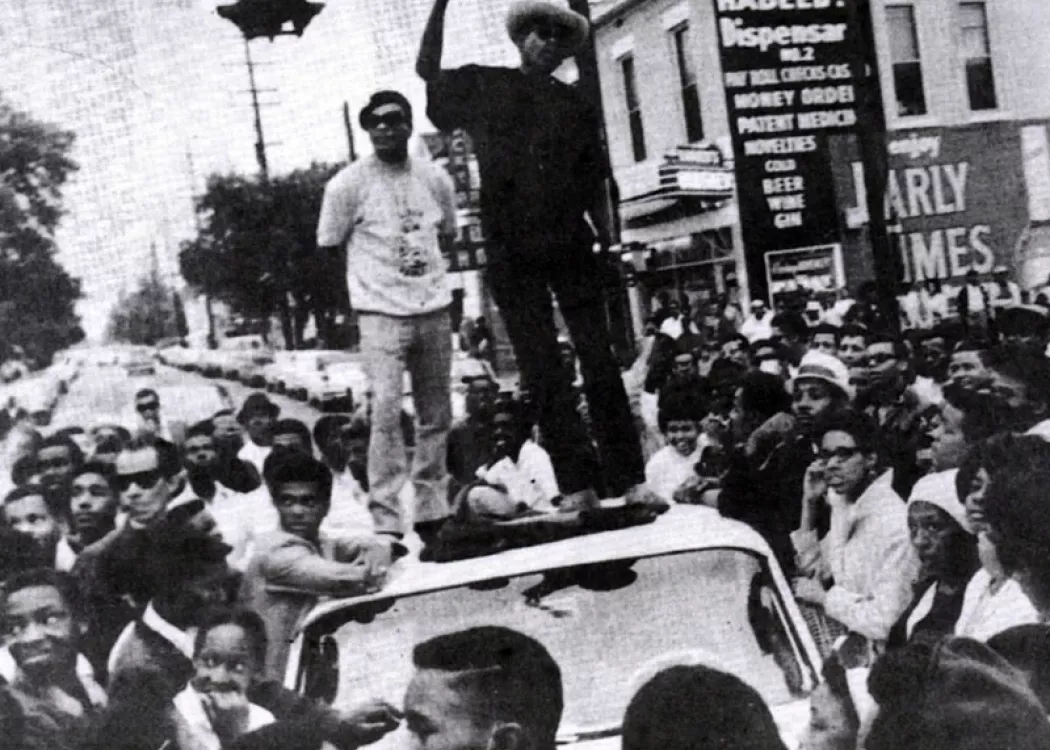 Historical image of men on top of a vehicle surrounded by a crowd