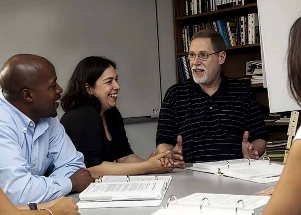 A group of scholars around a table discussing the engaged scholarship report