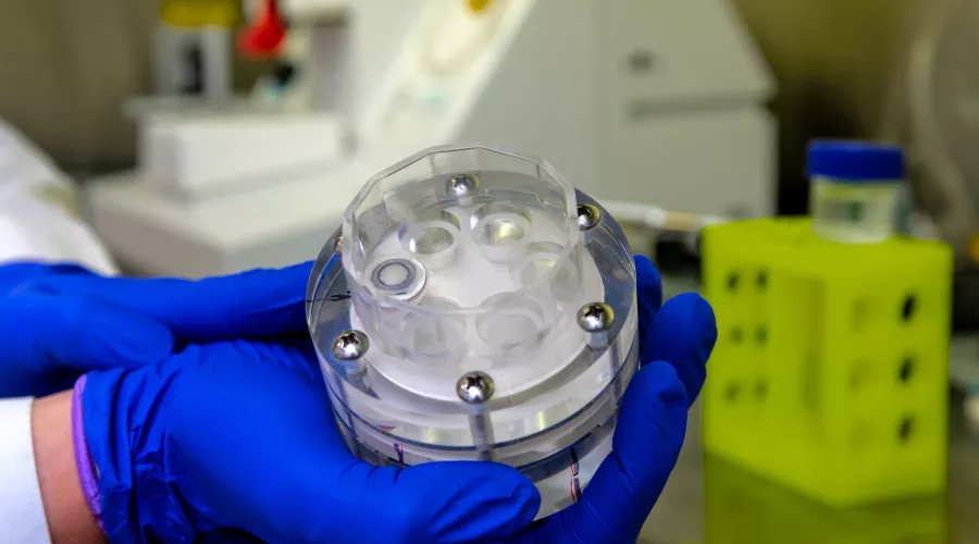 Close-up of a researcher in a lab holding a piece of lab equipment
