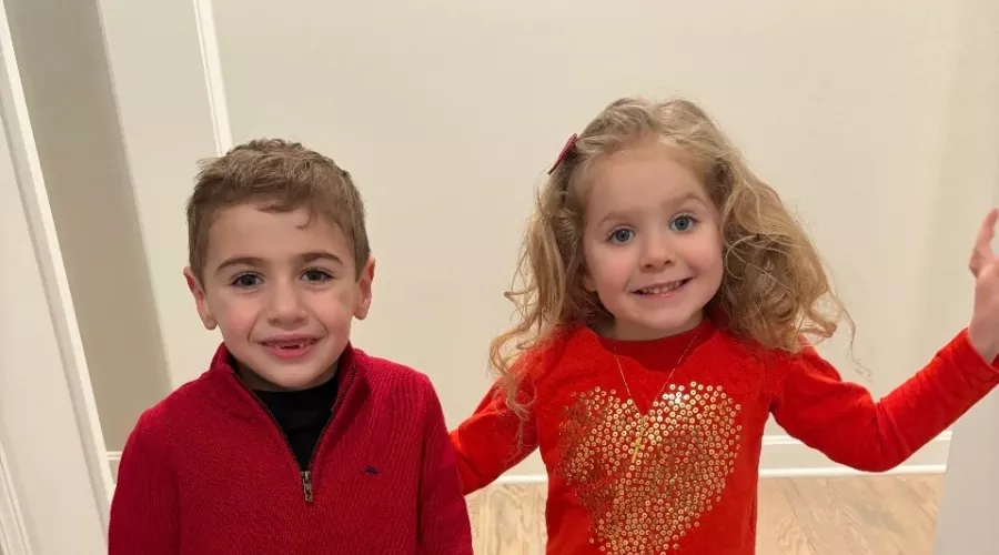 Two children dressed in red standing in a hallway