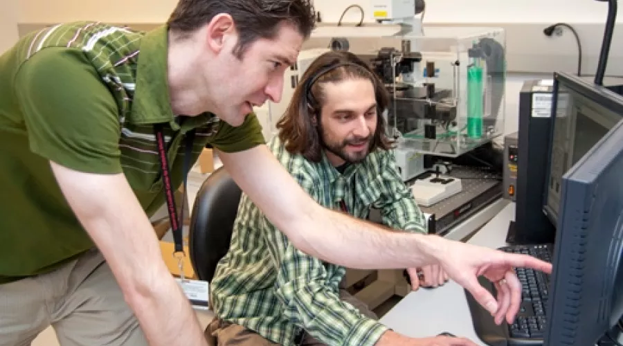 Two men working at a computer in a laboratory.
