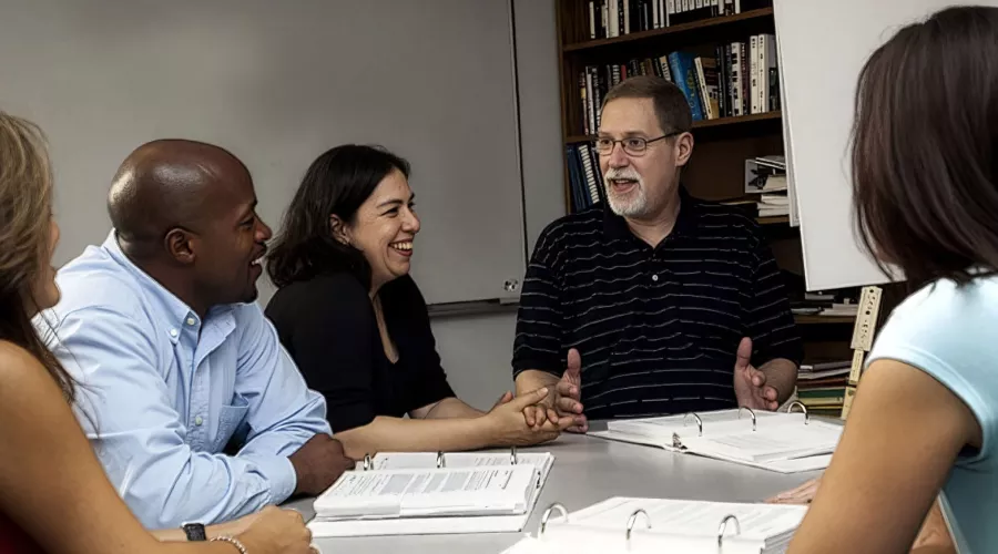 A group of scholars around a table discussing the engaged scholarship report